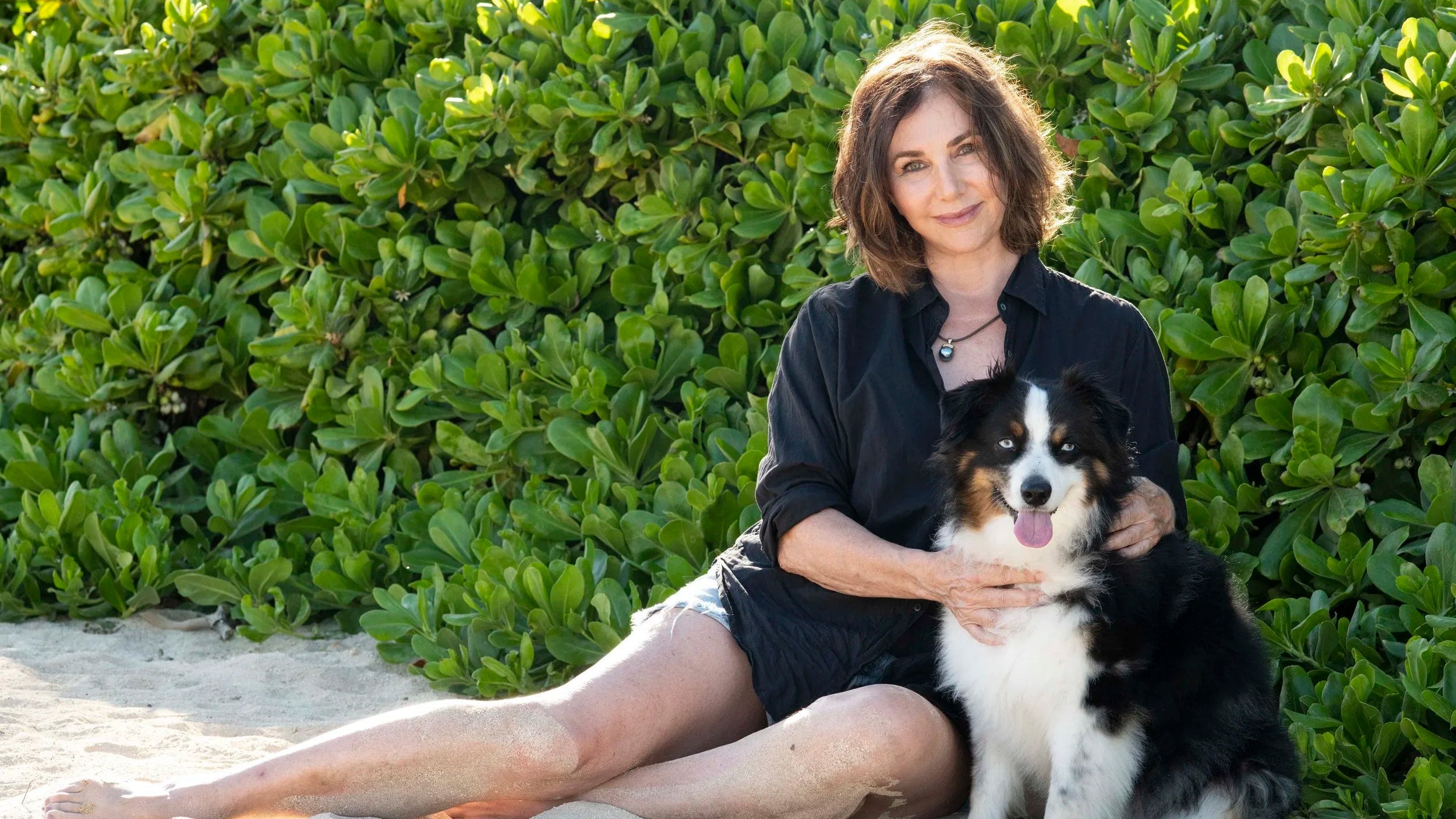Kim McDonald sitting with her dog on the beach.